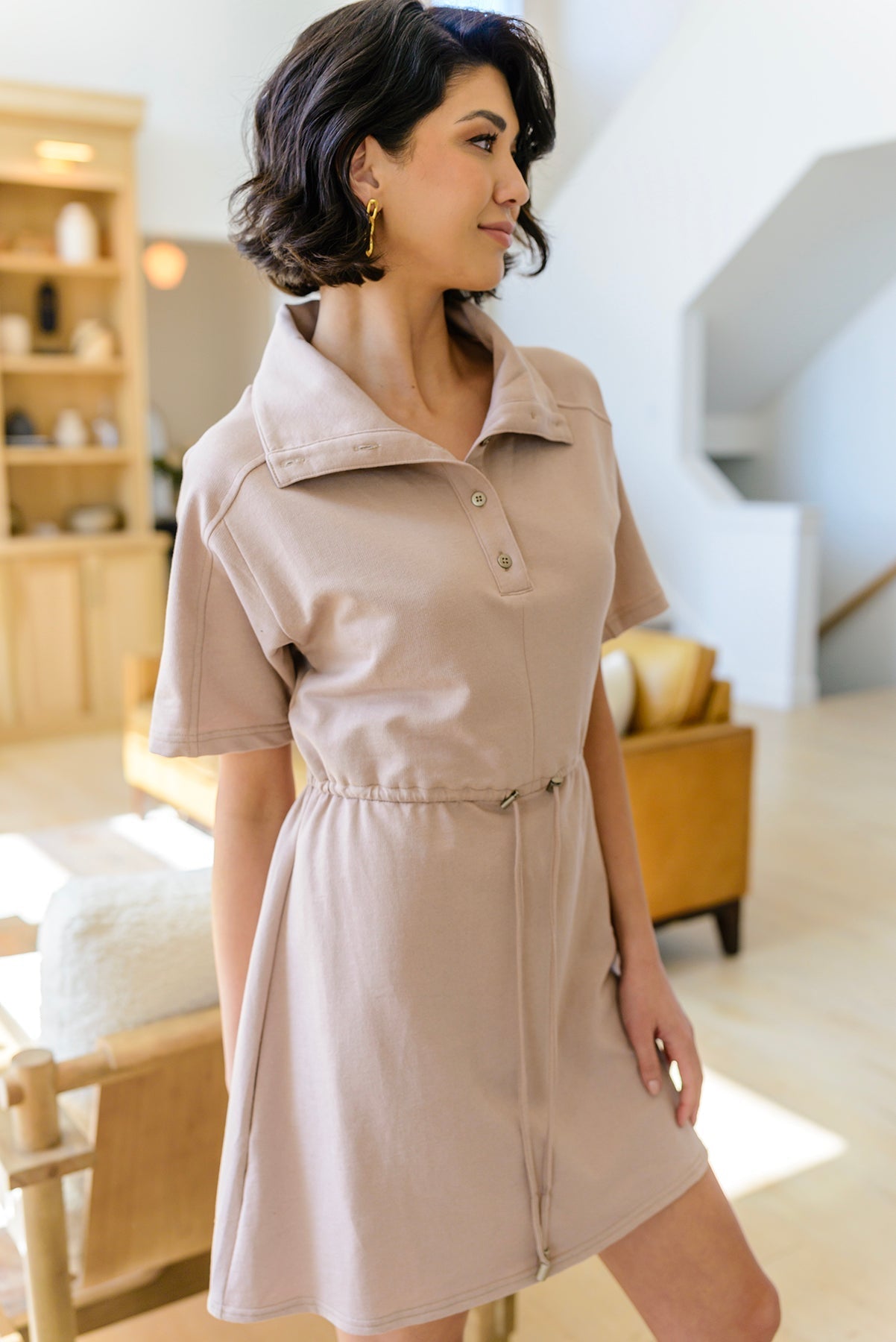 Woman wearing a beige dress in a living room setting