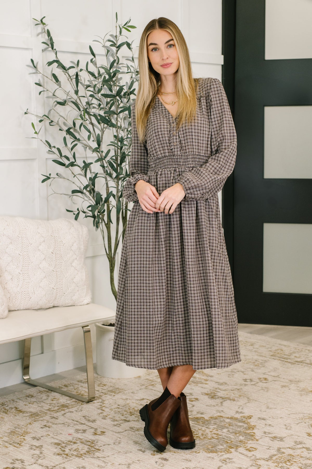 Brown plaid midi dress with a V-neckline, smocked waist, and functional pockets.