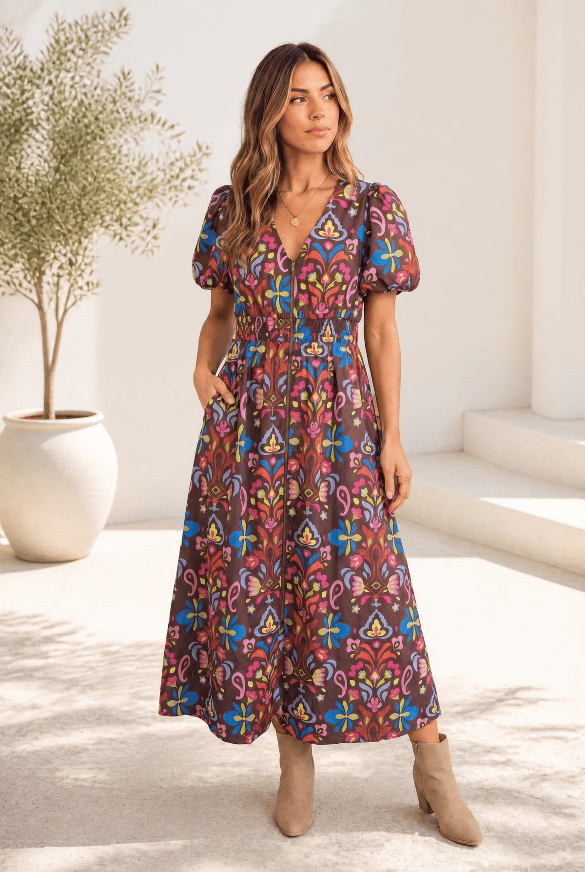 A woman wearing a chocolate brown midi dress with a colorful floral pattern and puff sleeves.