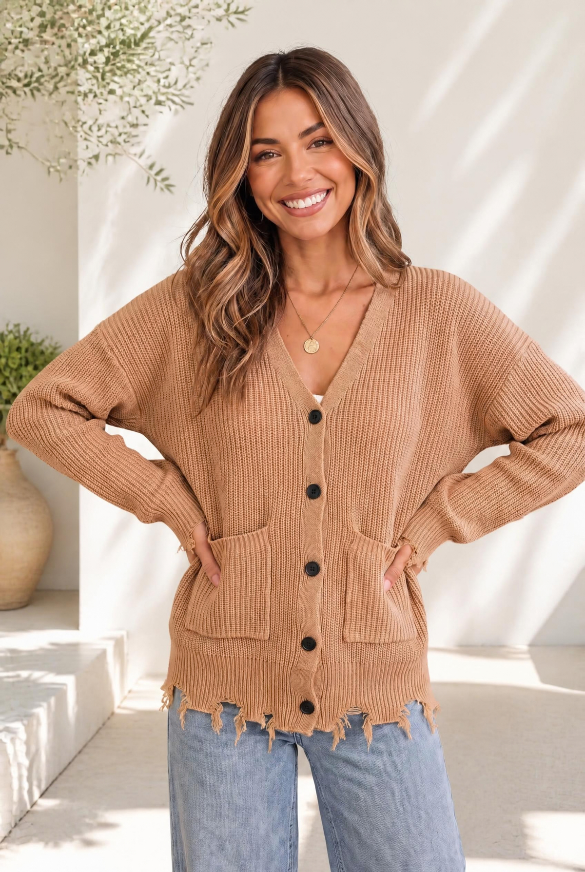 Camel-colored chunky knit cardigan with distressed hem, button-down front, and patch pockets.