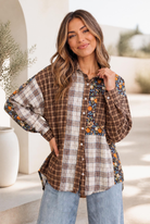 A mixed media button-down shirt with a plaid and floral patchwork design, shown on a model against a cozy backdrop.