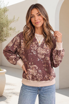 Woman wearing a mocha sweatshirt with vintage floral print and cream ribbed trim.