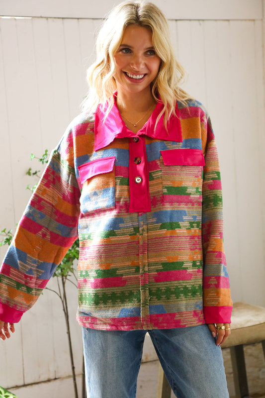 Woman wearing a colorful patterned shirt with a pink collar indoors.