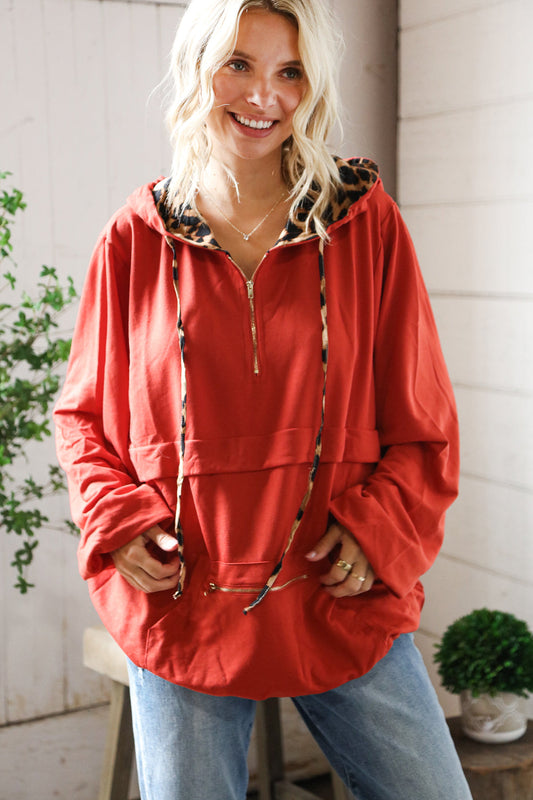 Woman wearing a red jacket with a leopard print hood indoors