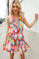 Woman wearing a colorful dress against a white brick wall.