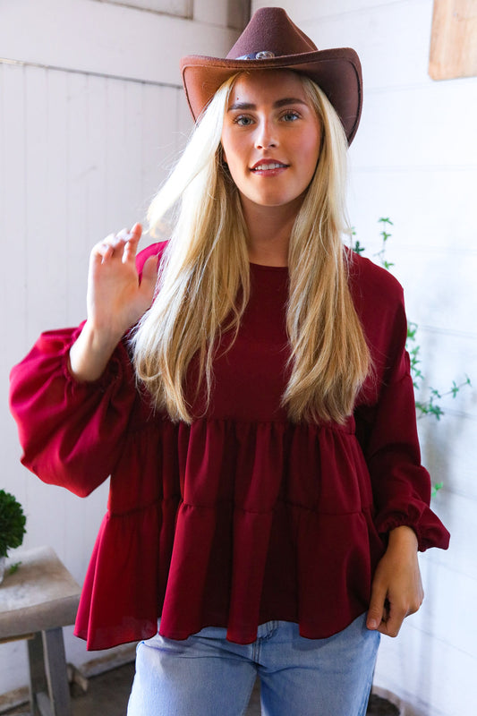 Woman wearing a red blouse and brown cowboy hat indoors