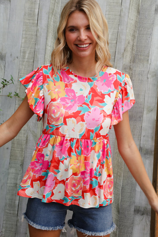 Woman wearing a colorful floral blouse with ruffled sleeves against a wooden background