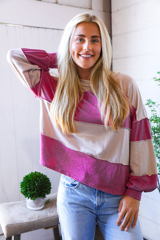 Woman wearing a colorful striped sweatshirt top and jeans indoors.