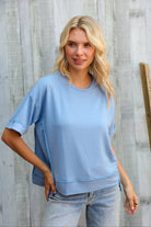 Woman wearing a light blue oversized shirt against a wooden background