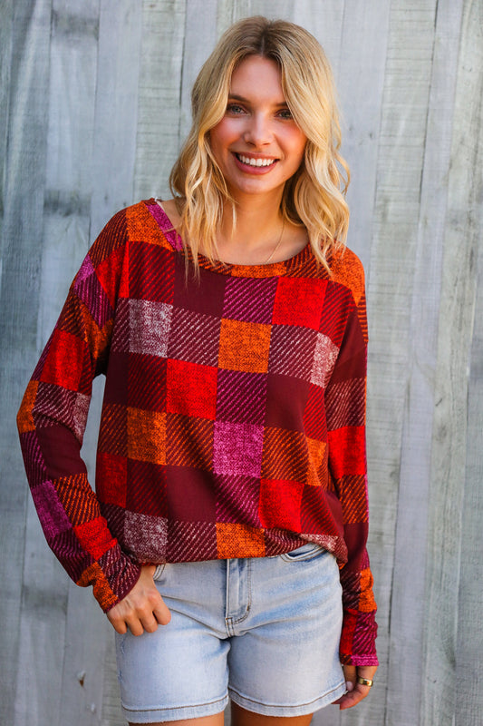 Woman wearing a colorful plaid sweater and denim shorts against a wooden background