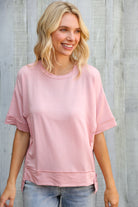 Woman wearing a pink oversized t-shirt against a wooden background