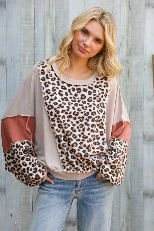 Woman wearing a leopard print long sleeve top against a wooden background