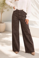 Wide leg high rise jeans in washed brown denim with large patch pockets and a raw hem.