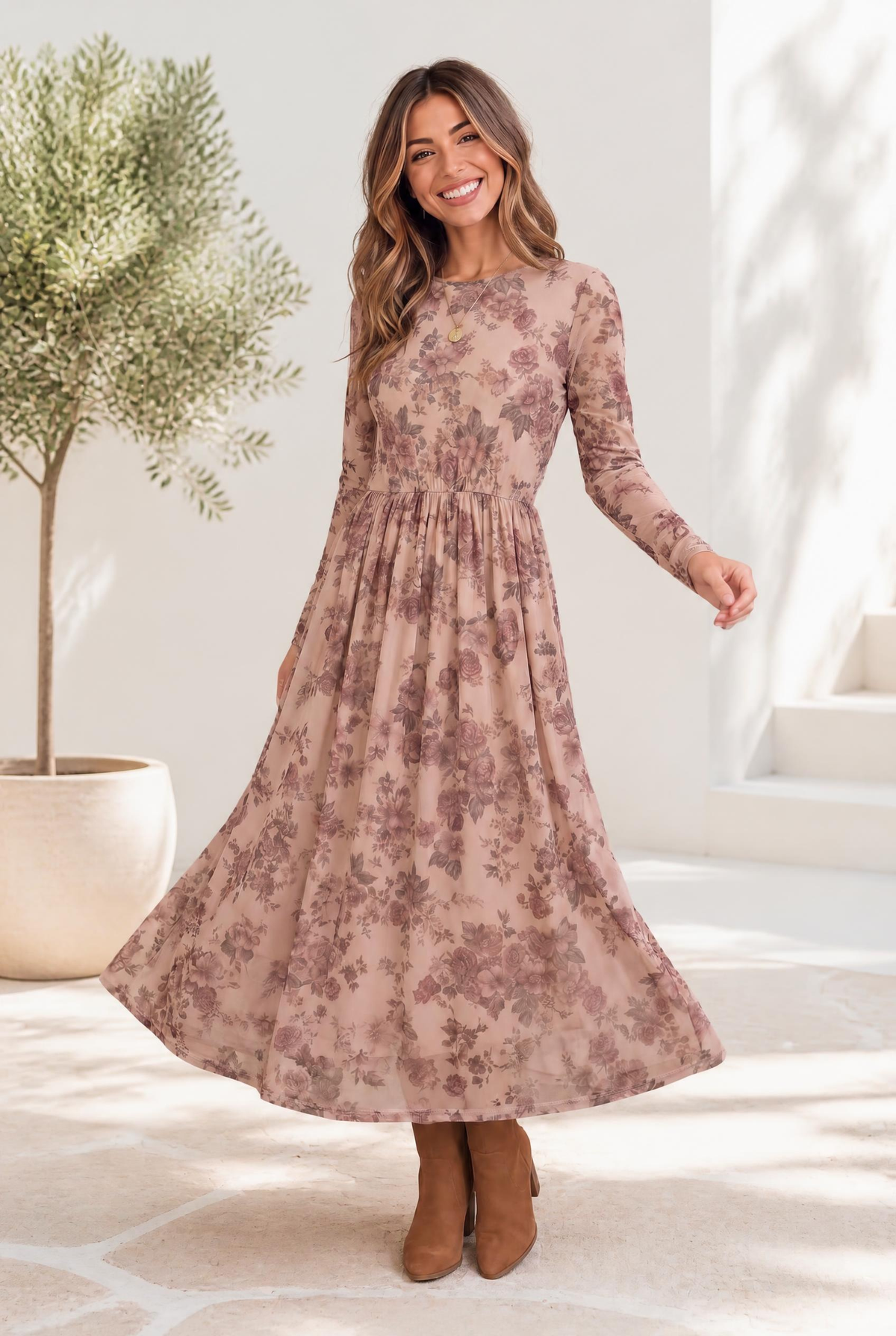 A woman wearing a blush midi dress with dusty rose floral print, long sleeves, and a flowing skirt.
