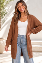 Woman wearing a caramel open front cardigan with a white tank and jeans.