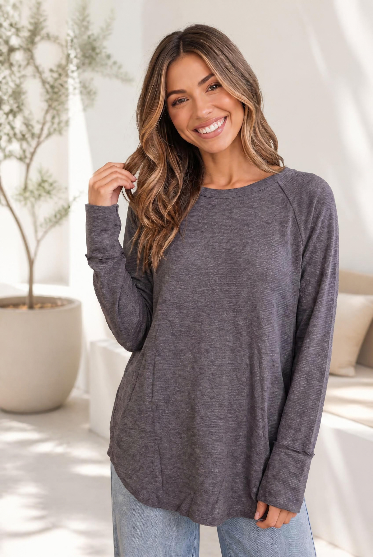 Woman wearing a slate-colored, long-sleeve raglan top with a waffle knit texture.