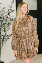 Woman wearing a leopard print dress with tassels in an indoor setting