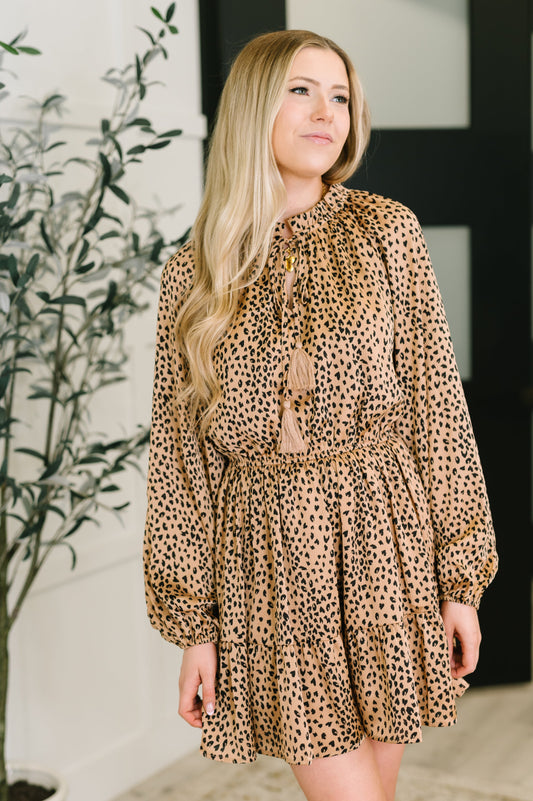 Woman wearing a leopard print dress with tassels in an indoor setting