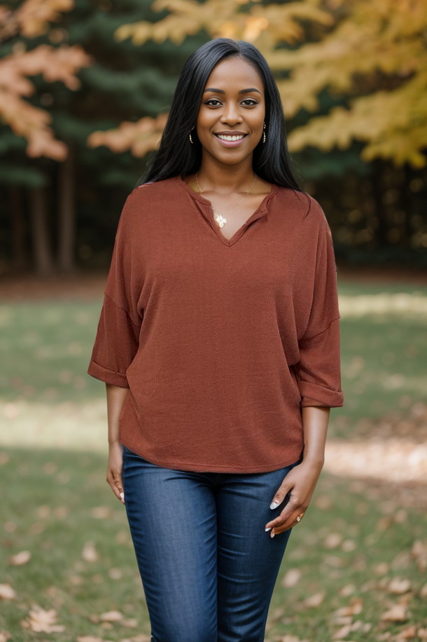 Woman wearing a rust-colored 3/4 sleeve knit top with a V-neck, standing outdoors.