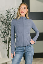 Woman wearing a heather gray zip-up jacket with a high neck and thumb holes.