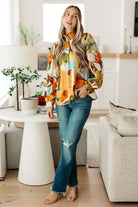 Woman in a colorful shirt and jeans standing in a modern living room.