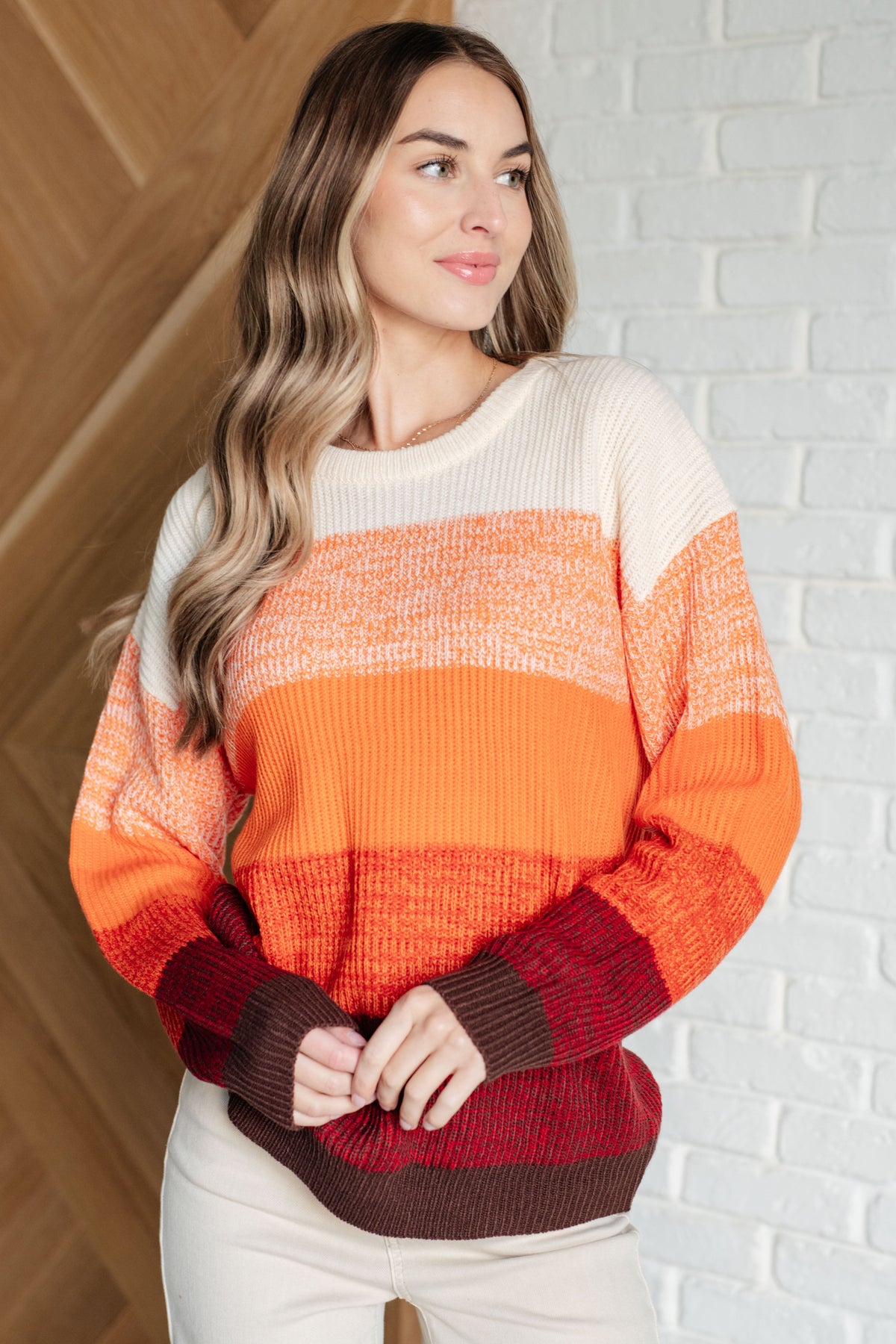 Woman wearing a multicolor color block sweater with a round neckline and drop shoulder design.