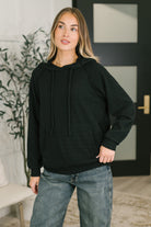 A black textured pullover with a hood, drawstring, raglan sleeves, and kangaroo pocket.