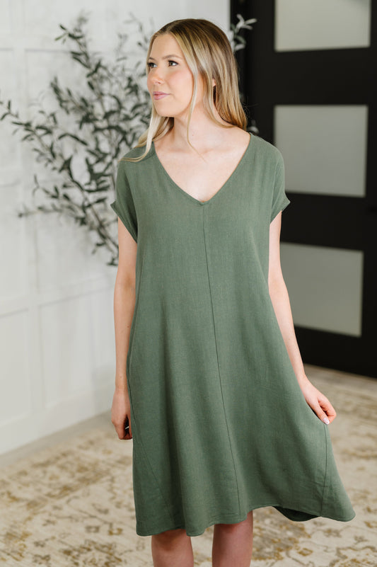 Woman wearing a green dress standing indoors with decorative elements in the background
