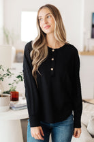 Woman wearing a black sweater with buttons in a bright room