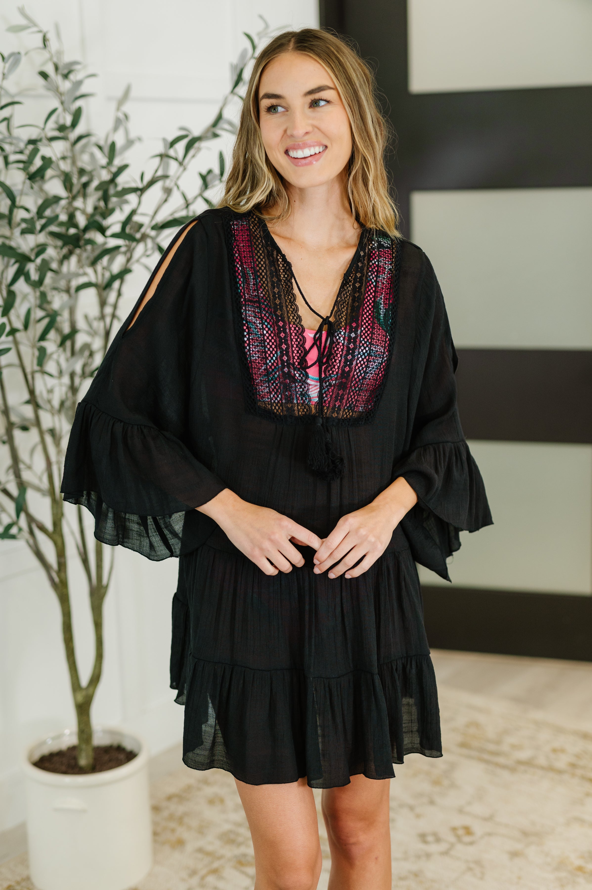 Woman wearing a black swim coverup dress in an indoor setting