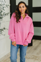Woman wearing a pink pullover shirt with a neutral background
