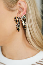 Earrings featuring a glossy plated alloy bow with a leopard print, shown on a model's ear.