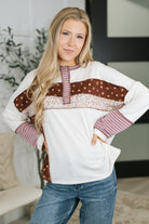 A woman wearing a color block henley with banded round neckline and exposed seam details in soft French terry.