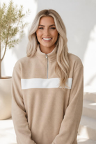 A beige fleece sweatshirt with a white colorblock panel and half zip neckline.