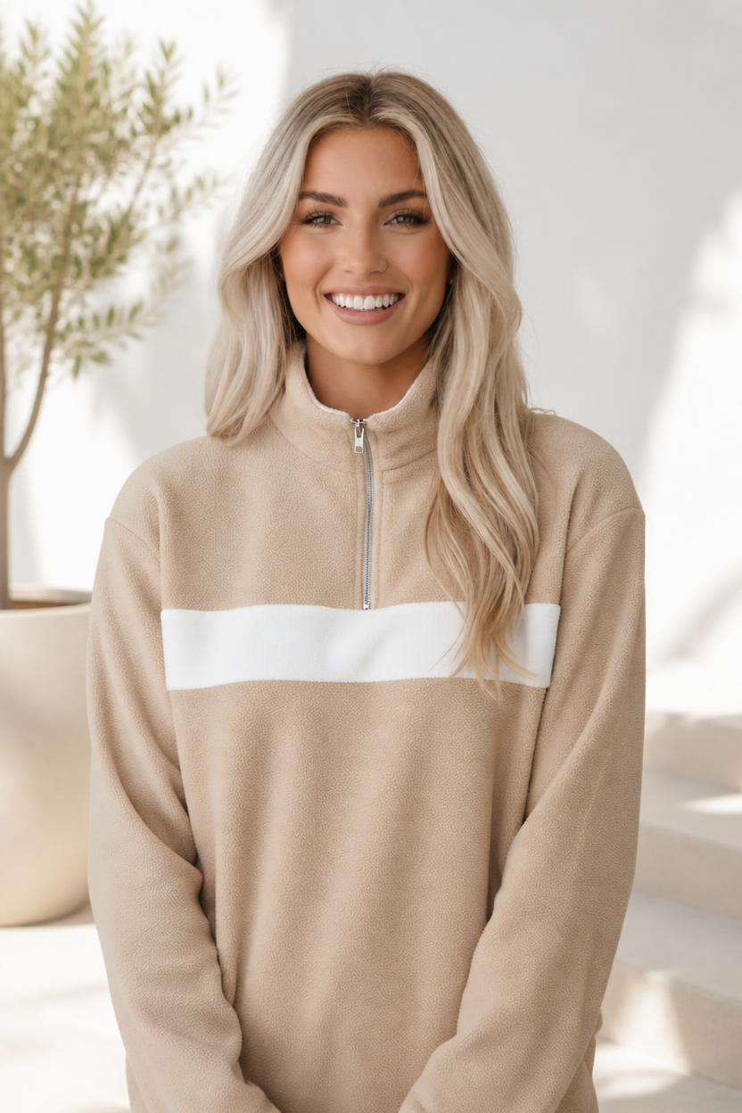 A beige fleece sweatshirt with a white colorblock panel and half zip neckline.