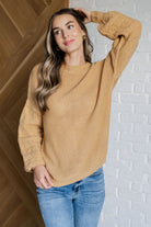 Wheat-colored sweater with round ribbed neckline and balloon sleeves worn by a model.