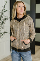 Woman wearing a patterned hoodie jacket and jeans indoors