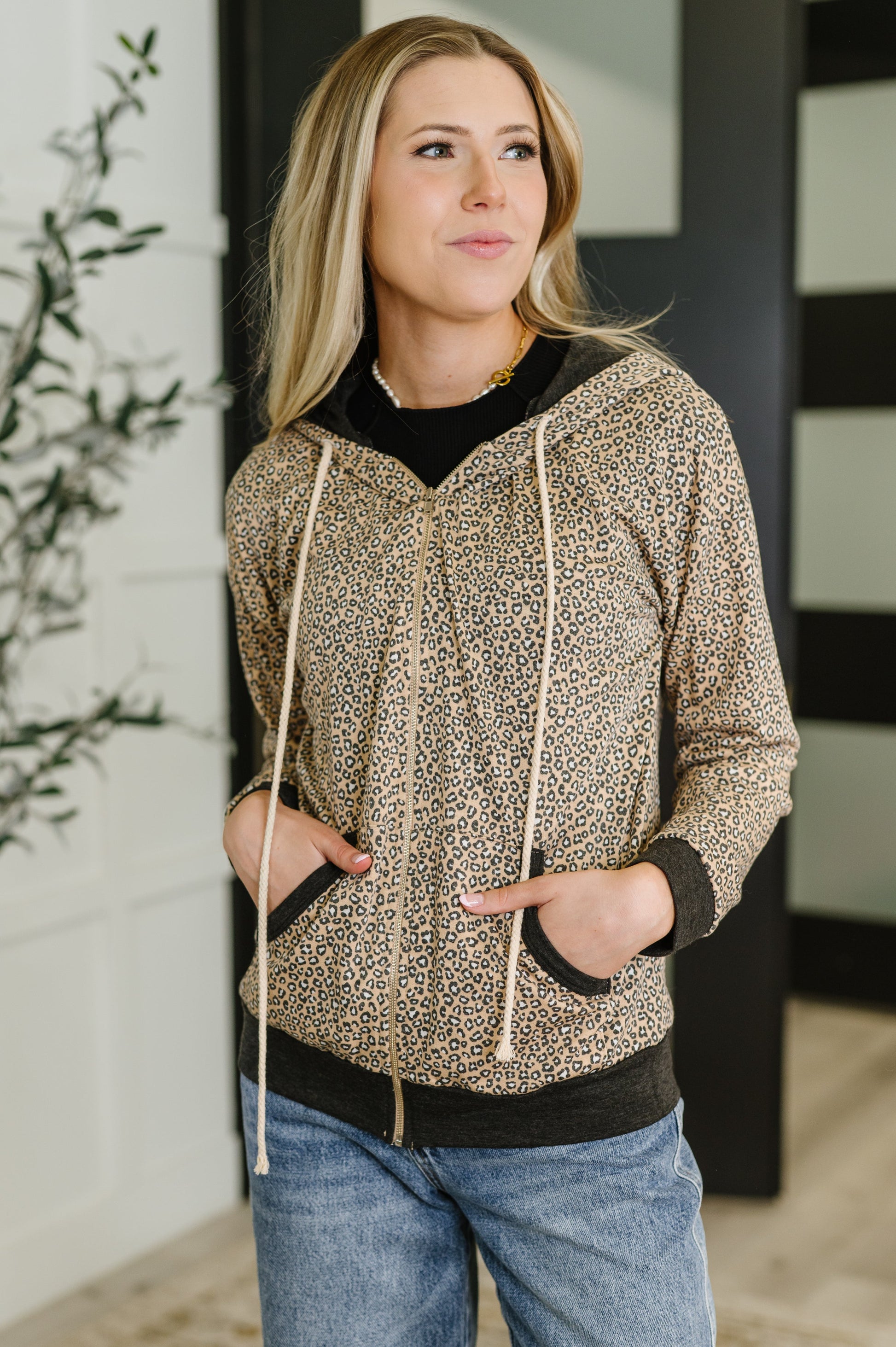 Woman wearing a patterned hoodie jacket and jeans indoors