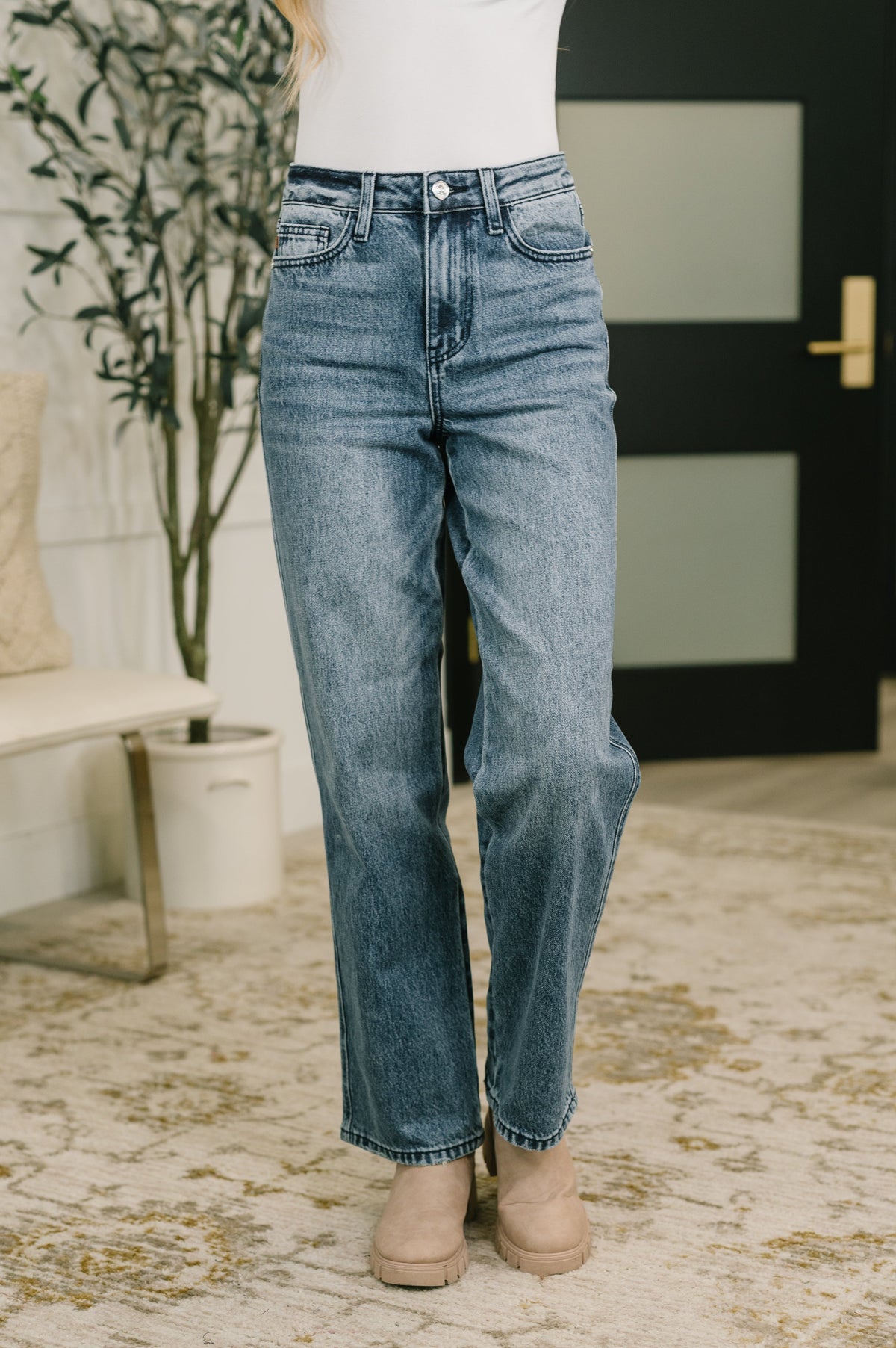 A model wearing high-waisted straight-leg jeans in a medium indigo wash.