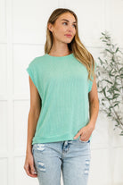 A woman wearing a mint green, banded round neckline, short sleeve, and a banded hemline casual knit top with a relaxed fit.