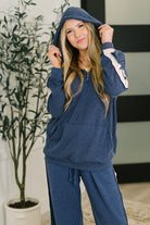 Woman wearing a blue waffle knit hoodie and pants in a home setting.