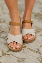 Womens Beige sandals with brown soles on a textured surface