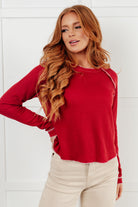 Woman wearing a red shirt and beige pants against a white background