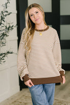 Woman wearing a striped long sleeve shirt with brown trim in a home setting