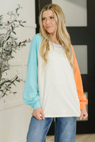 A woman wearing a color block top with raglan sleeves in soft jersey knit.