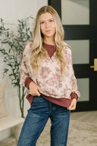 A woman wearing a floral and ribbed pullover with a relaxed fit and exposed seam details.