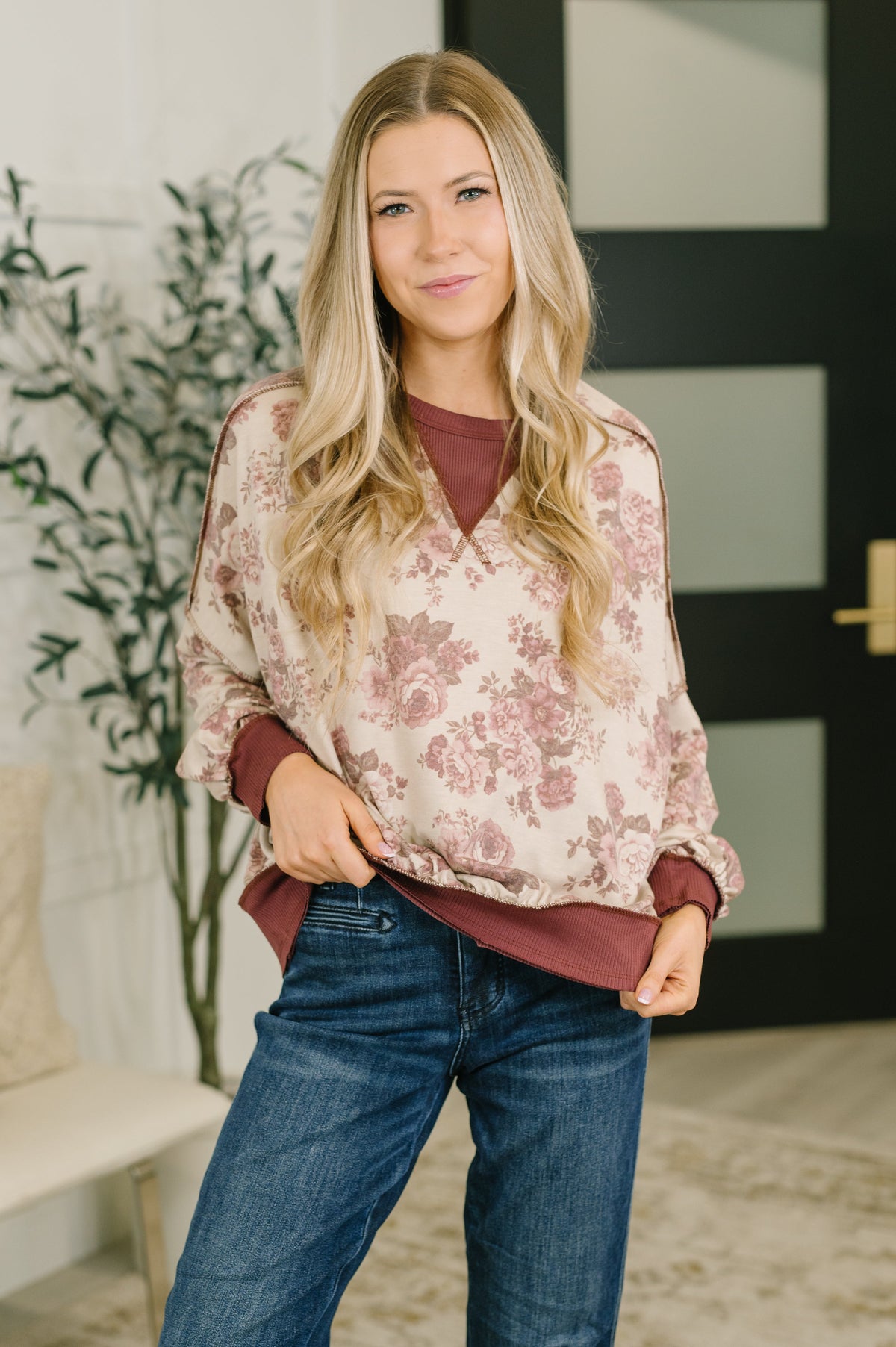 A woman wearing a floral and ribbed pullover with a relaxed fit and exposed seam details.