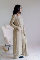 Woman wearing a light olive three-piece set with a tank, long cardigan, and wide-leg pants.