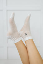Sheer knit ankle socks with a machine-embroidered bow detail and white trim.