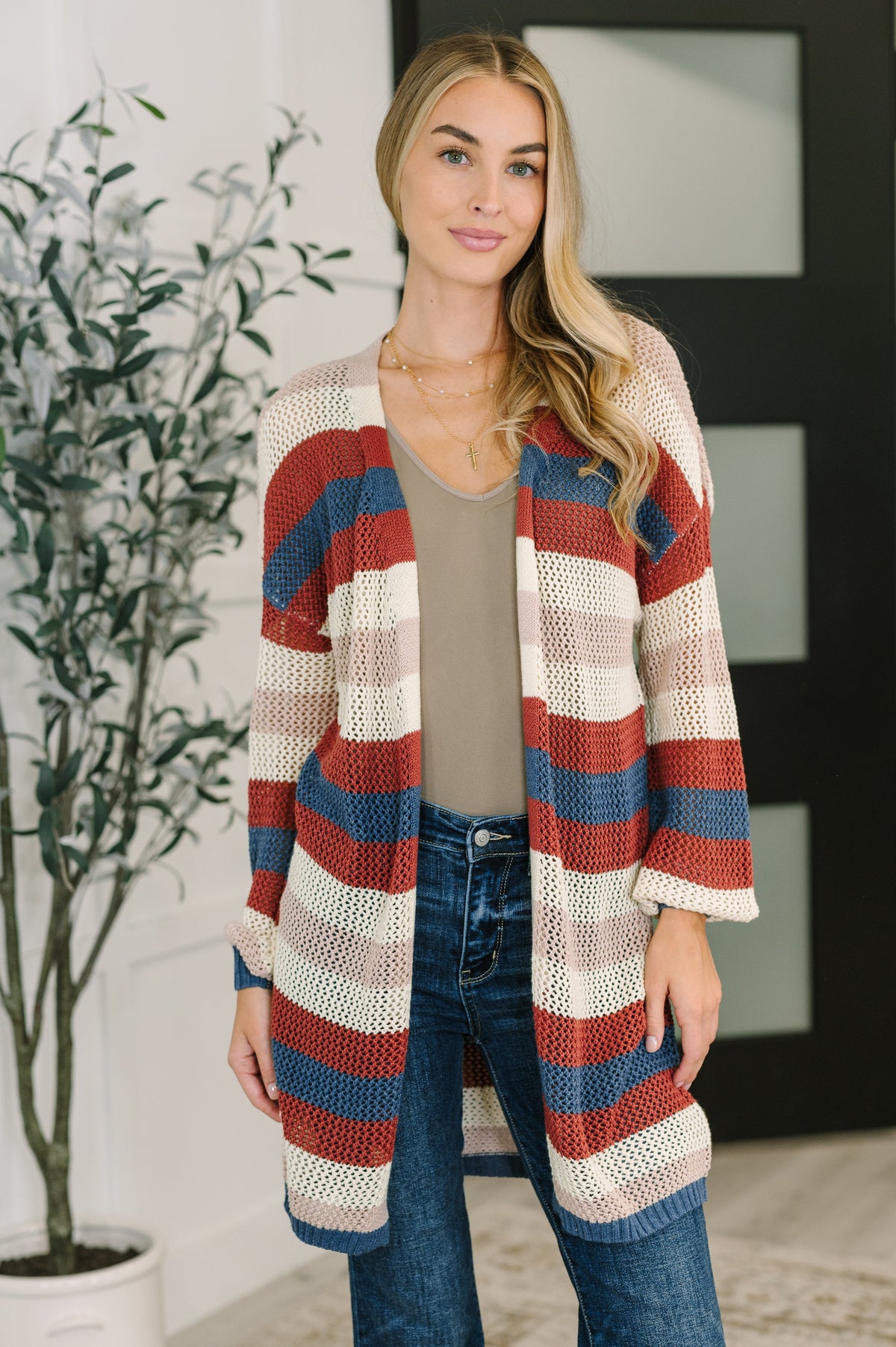 A woman wearing a striped knit cardigan with an open front, banded ribbed cuffs, and hem.